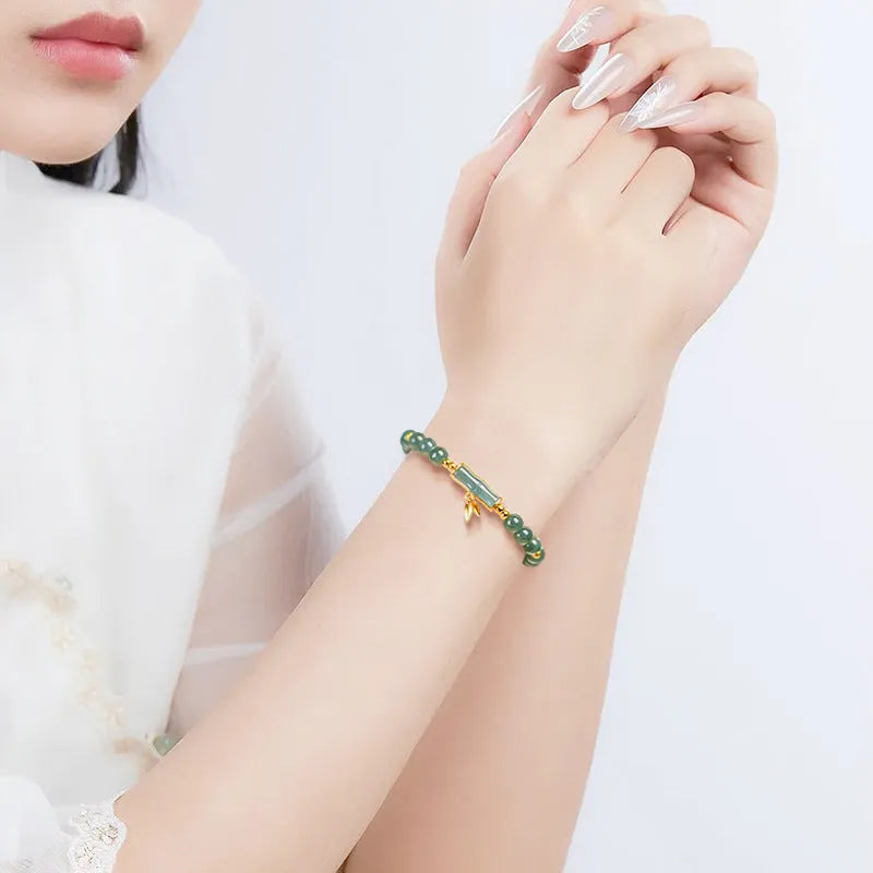 Simple sterling silver bracelet with a raised setting holding a natural blue jade round bead.