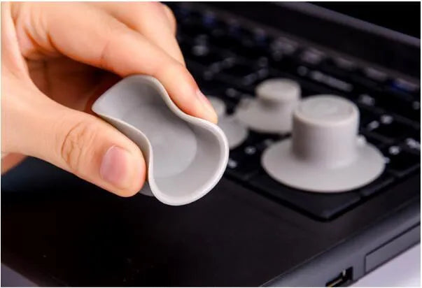 Four grey plastic laptop cooling pads with silicone feet, two large and two small, on a wooden desk.