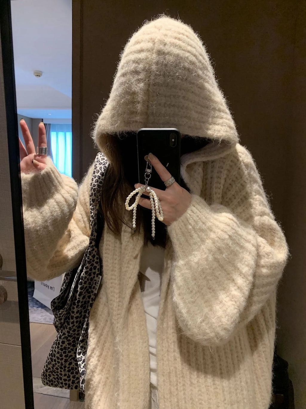 A woman wearing a thick, dark grey hooded cardigan with a loose, longline fit.