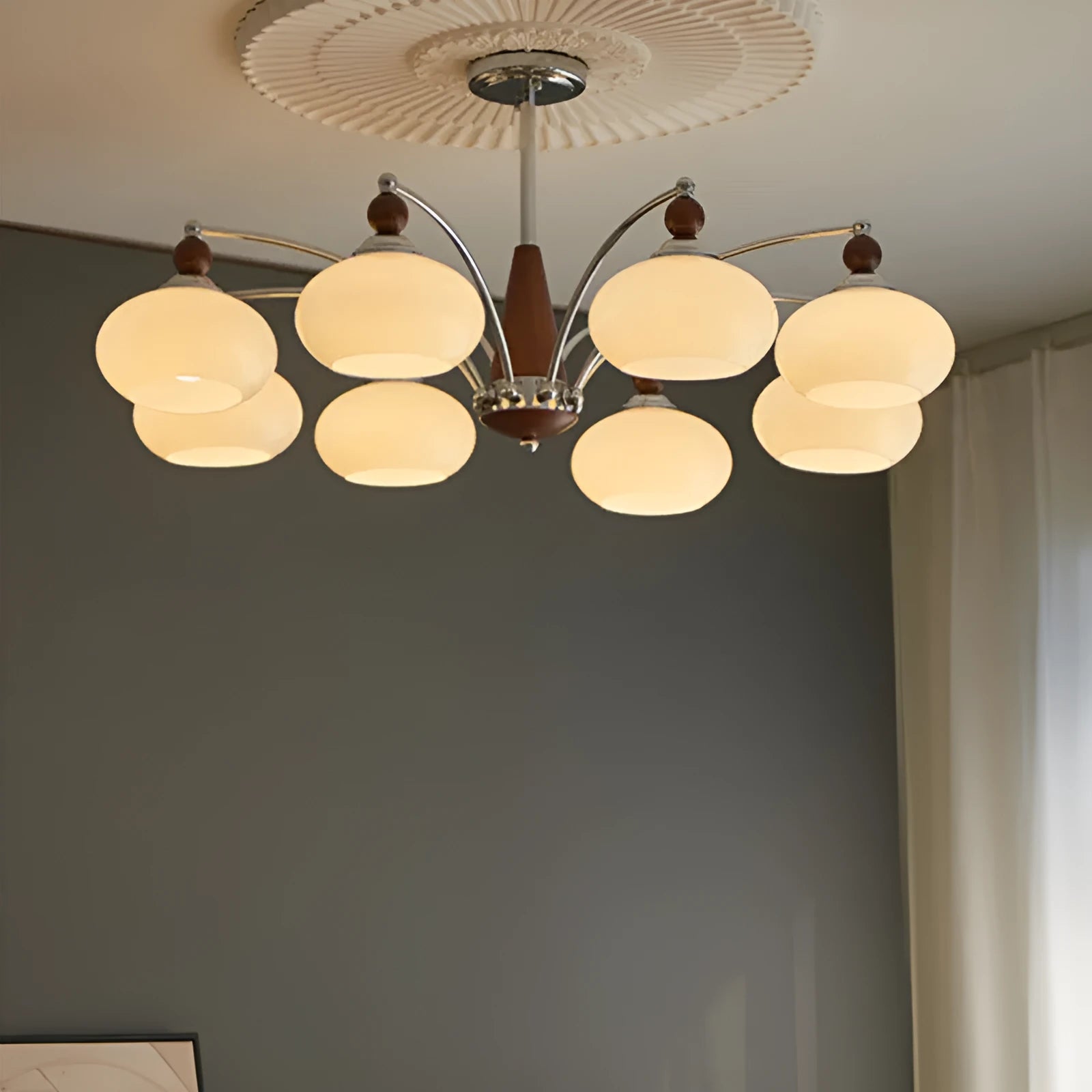 Traditional persimmon glass chandelier with multiple chrome arms and white glass lampshades hanging from a ceiling.