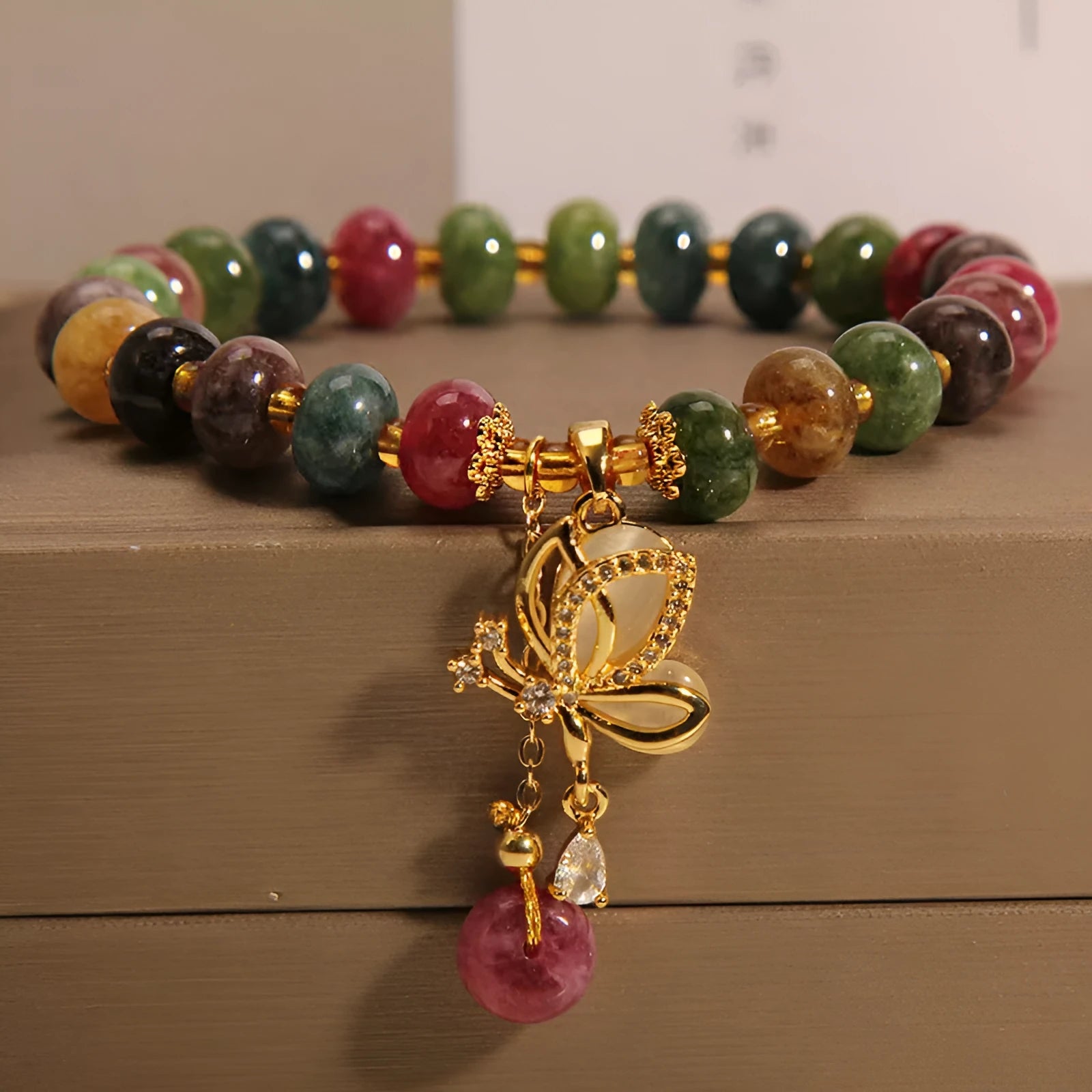 Women's colourful bracelet with alloy butterfly charm and tourmaline beads on wrist.