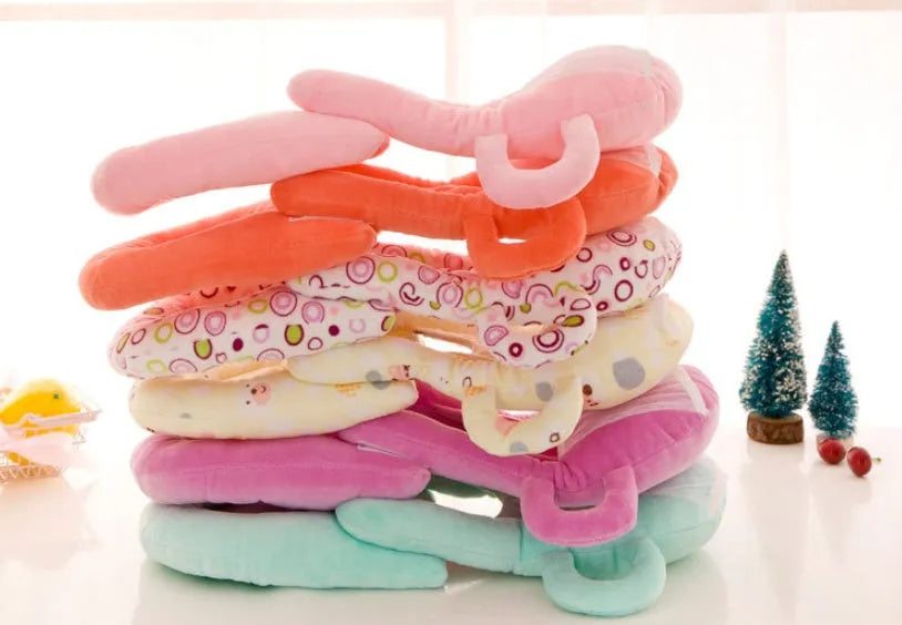 Pink plush baby feeding pillow on a carpet, showing its 30cm by 42cm size and soft texture.