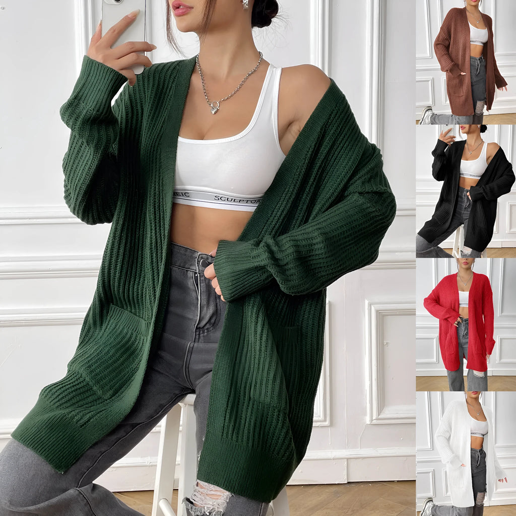 A woman wearing a dark green, mid-length acrylic cardigan with two front pockets.