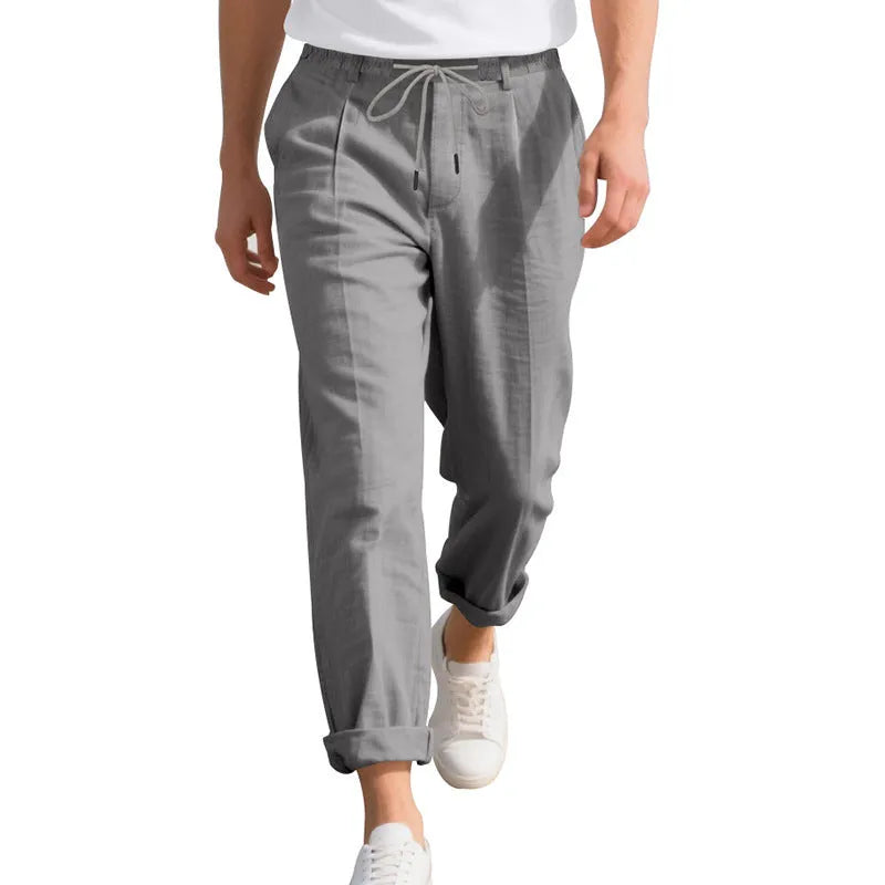 Men's light khaki linen trousers with a drawstring waist and straight leg on a hanger.