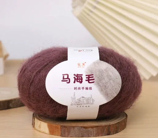 A ball of mohair yarn in a selected colour next to a hand-woven scarf example, showcasing the DIY kit.