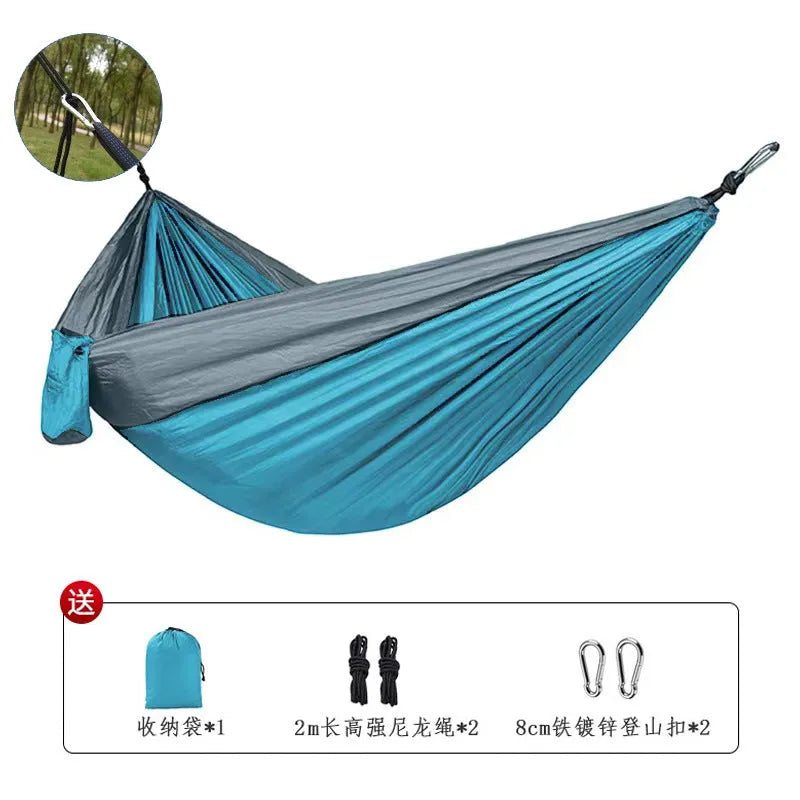 Sapphire blue parachute nylon hammock hung between two trees, showing its full 270cm length and integrated ropes.