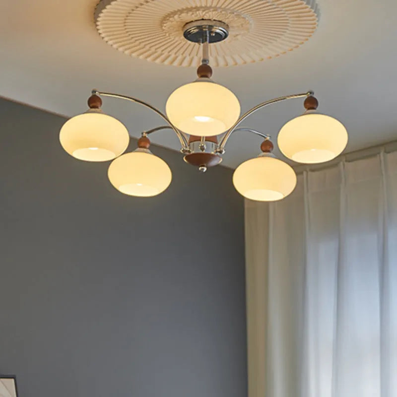 Traditional persimmon glass chandelier with multiple chrome arms and white glass lampshades hanging from a ceiling.