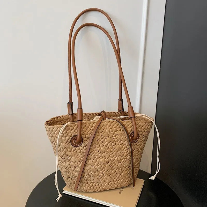 Beige woven shoulder bag with retro styling and dual-carry handles shown in horizontal square suitcase shape