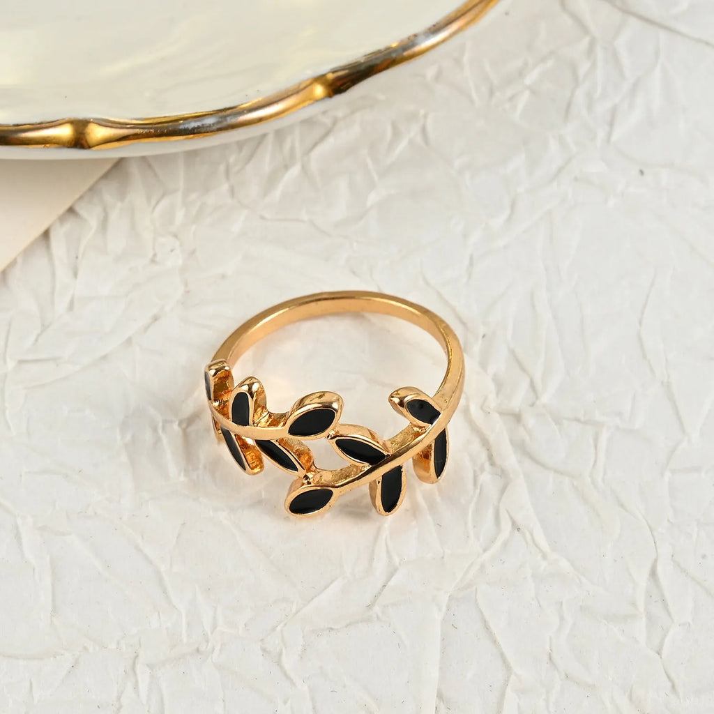 Gold electroplated acrylic ring with a geometric leaf and flower design on a model's index finger.