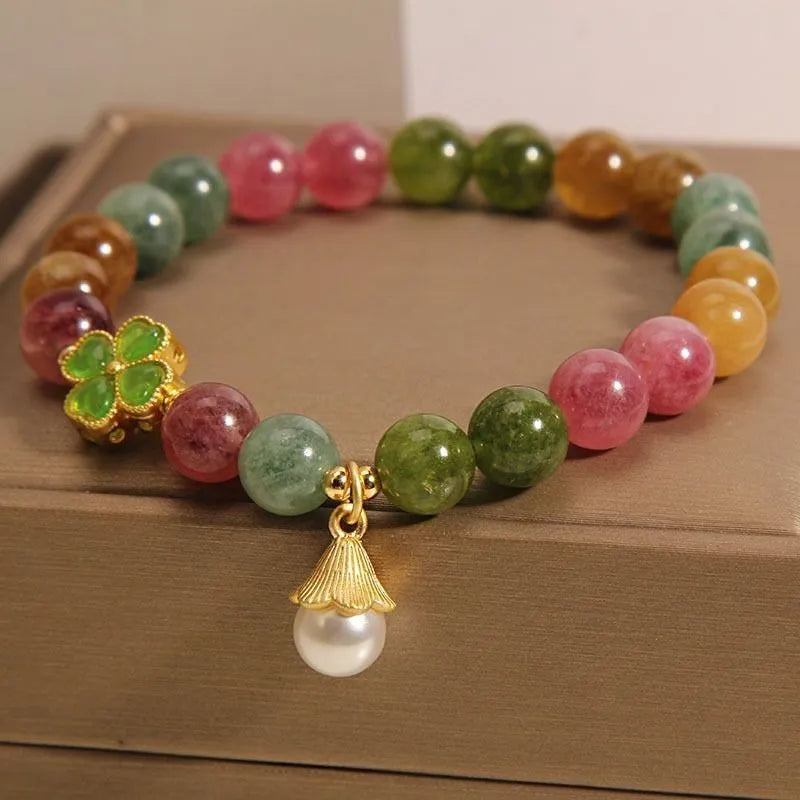 Natural colour tourmaline bracelet with four-leaf clover charm and pearl pendant on wrist