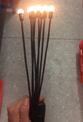 Solar-powered LED garden spike light with multiple glowing heads and a metal ground plug inserted in soil at dusk.