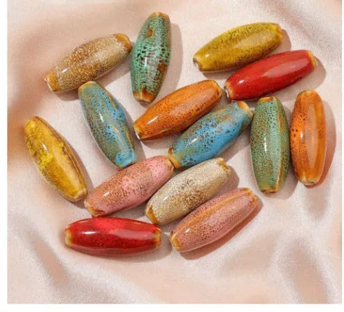 Assortment of ceramic bullet beads in pink, yellow, blue, red, coffee, green, orange, and mixed flower glaze colours.