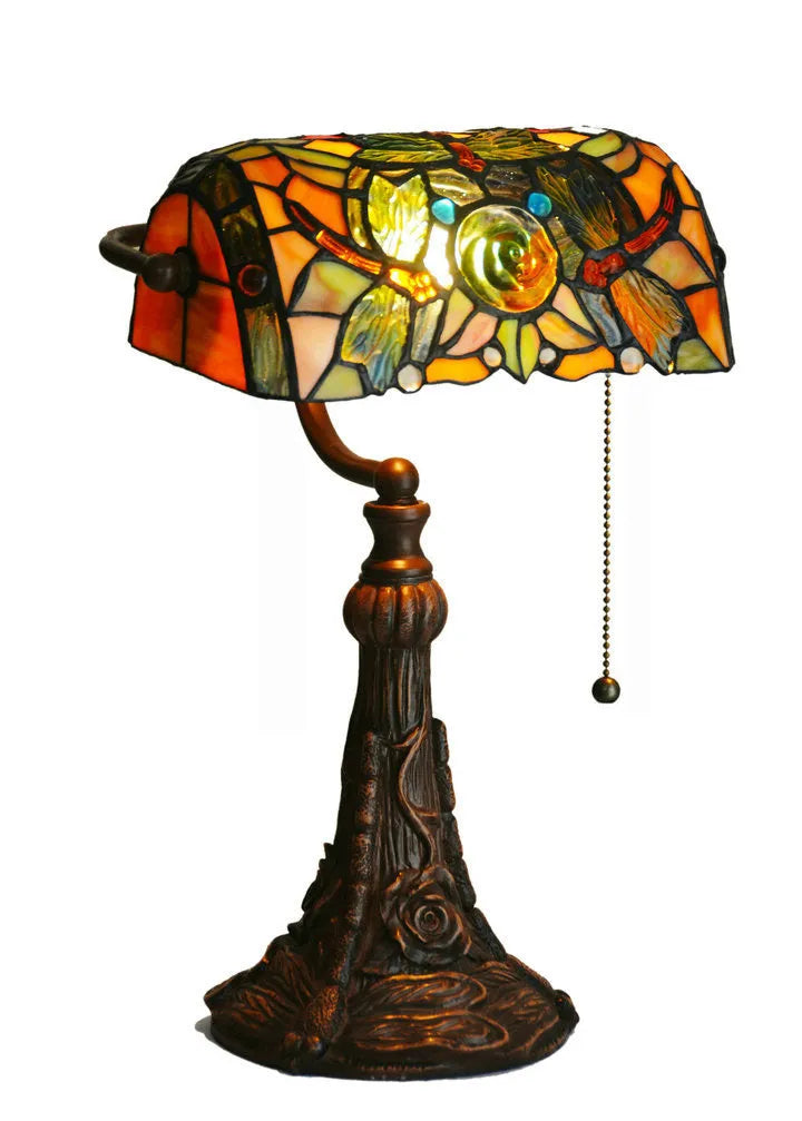 Tiffany style table lamp with coloured stained glass shade on a resin base, shown on a desk.