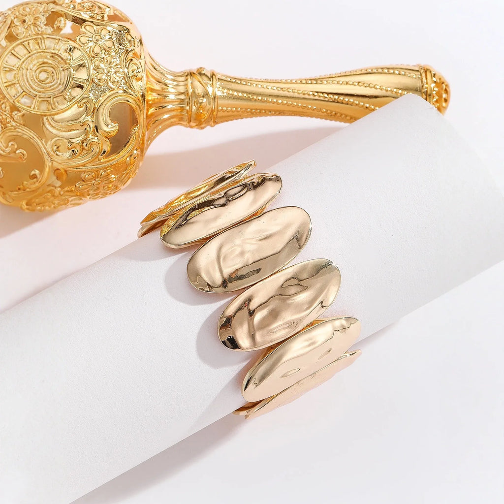 Gold exaggerated elliptical cuff bangle with 4mm band width on a neutral background