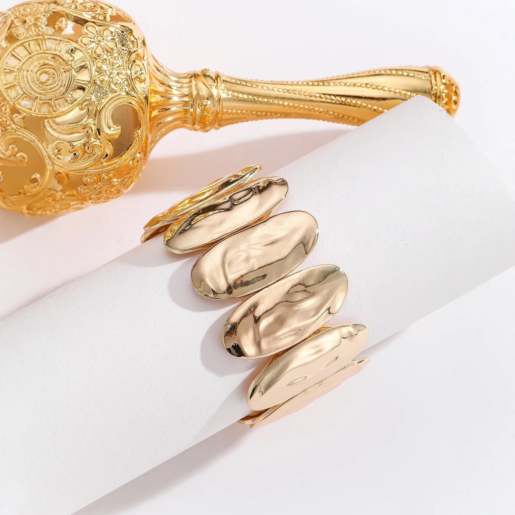 Gold exaggerated elliptical cuff bangle with 4mm band width on a neutral background