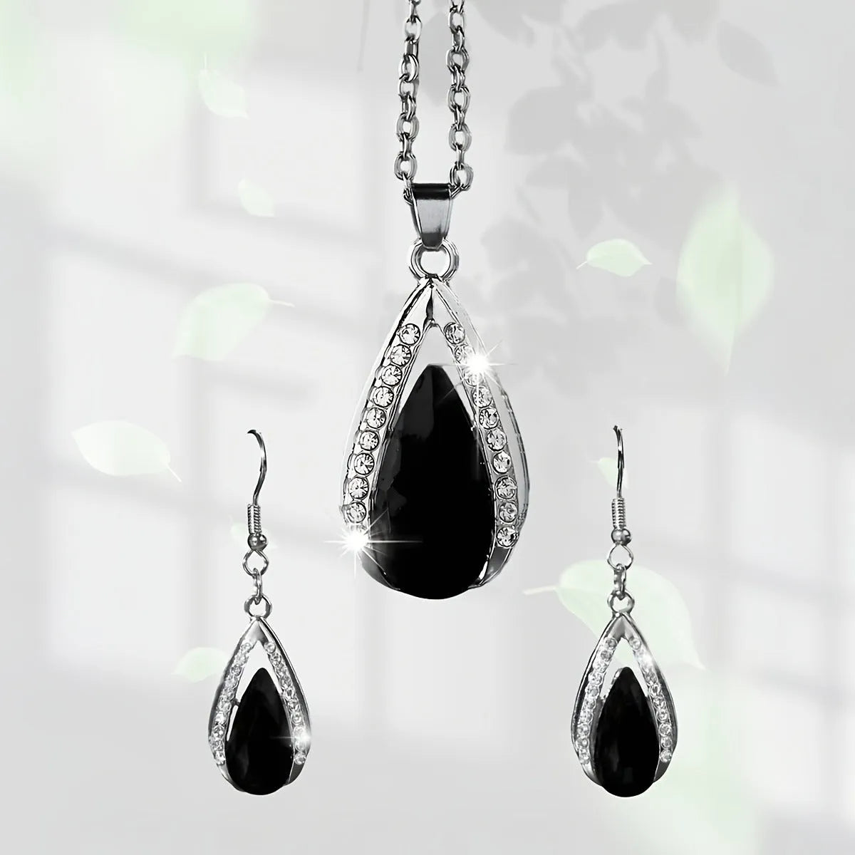 Black and red teardrop-shaped glass pendant necklace and matching stud earrings set on a grey background.
