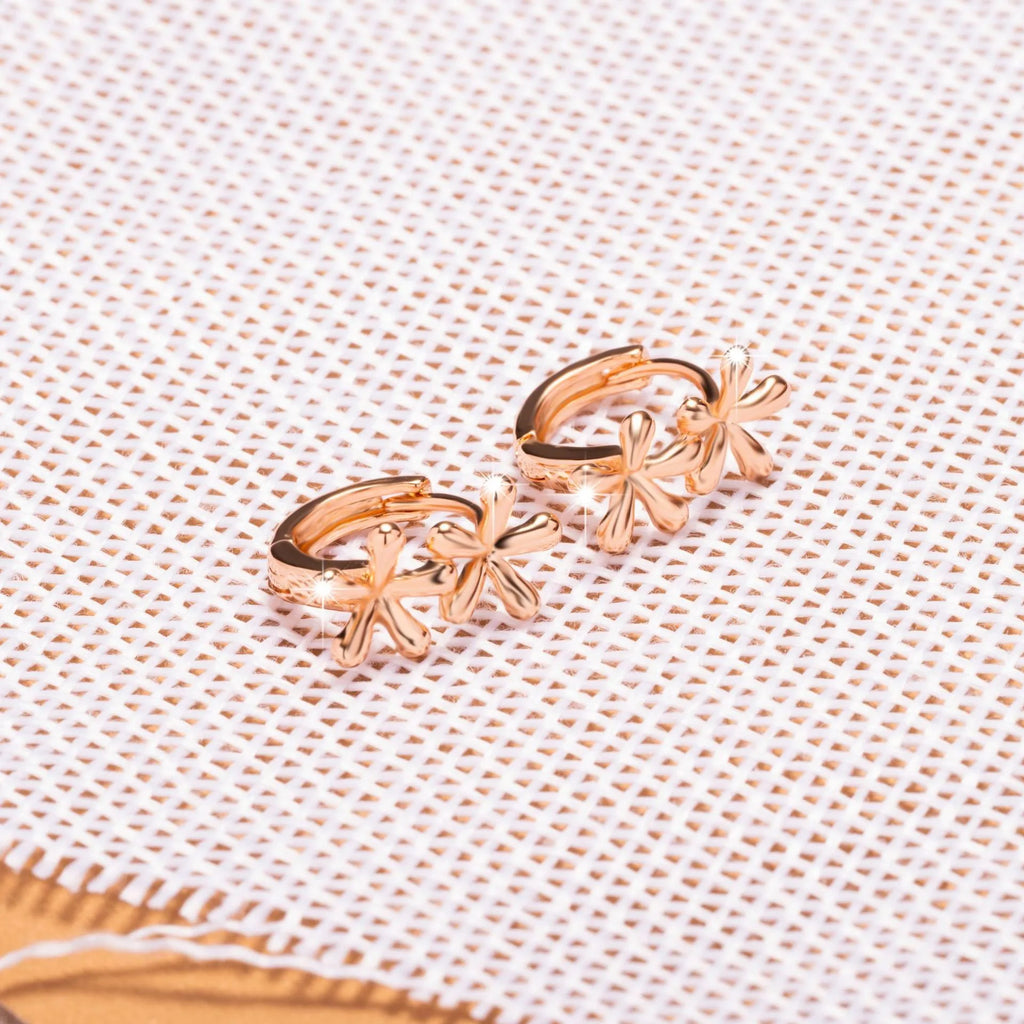Close-up of rose gold drop earrings with 3D floral and waterdrop design on a white background.