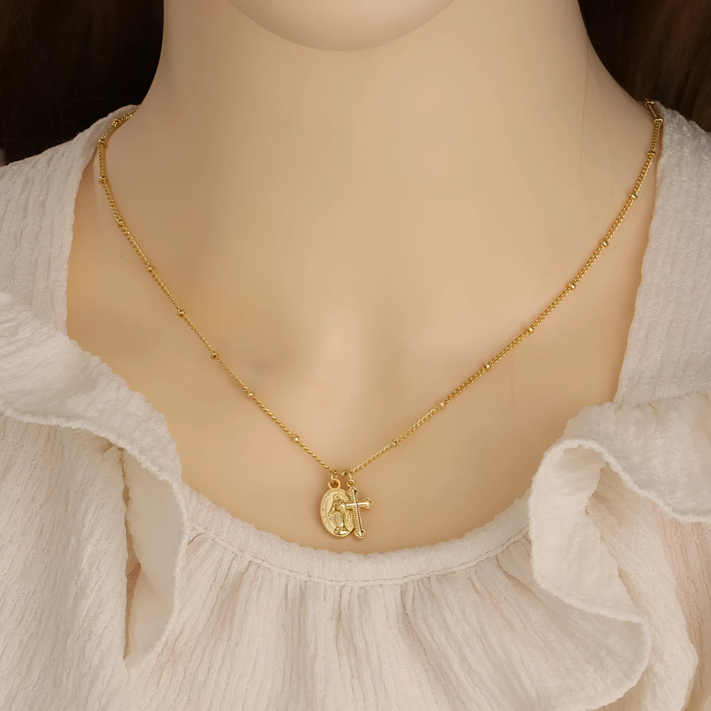 Gold geometric cross necklace with Virgin Mary detail on a 60cm chain, pendant is 3cm tall.