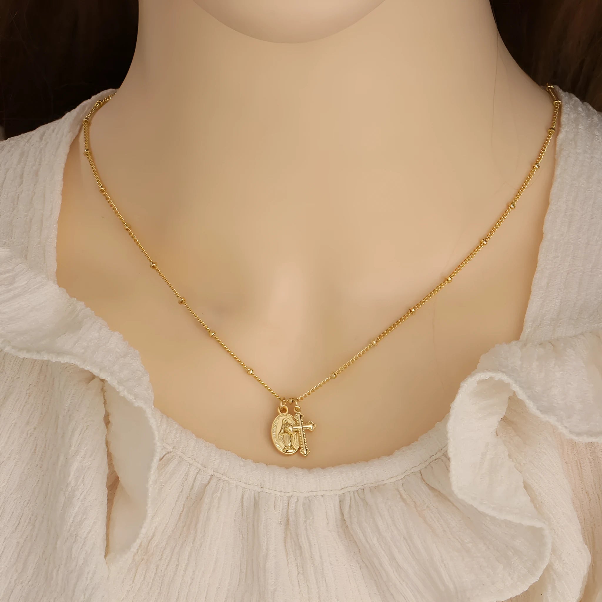 Gold geometric cross necklace with Virgin Mary detail on a 60cm chain, pendant is 3cm tall.