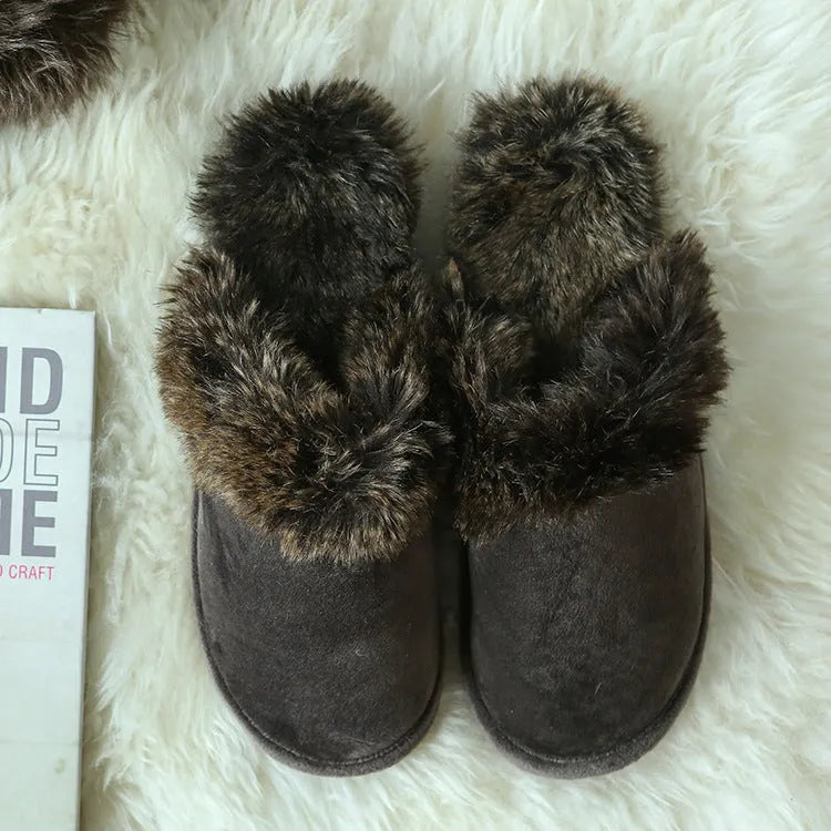Beige couple wool slippers with suede upper and artificial wool trim on a wooden floor