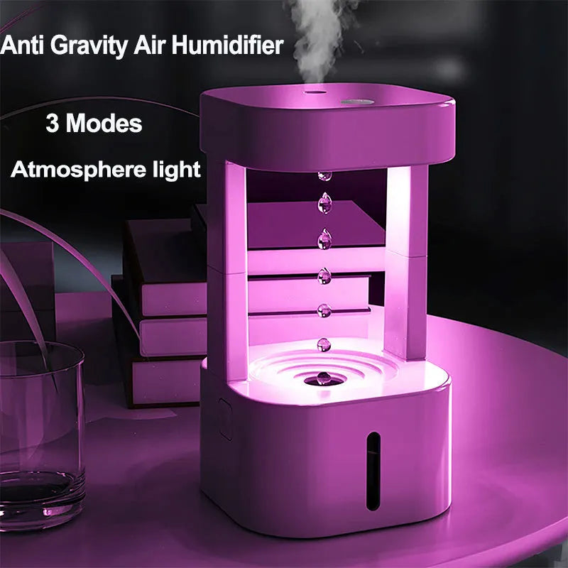 White anti-gravity water drop humidifier with coloured light on a desk next to USB cable