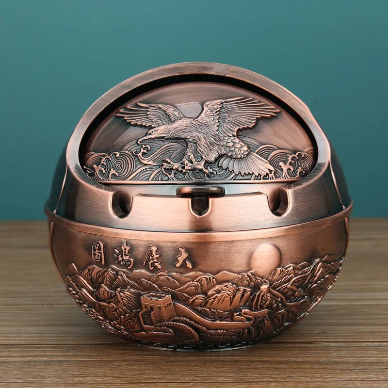 Alloy decorative ashtray in bronze with ornate peacock motif and cigarette extinguishing slot.