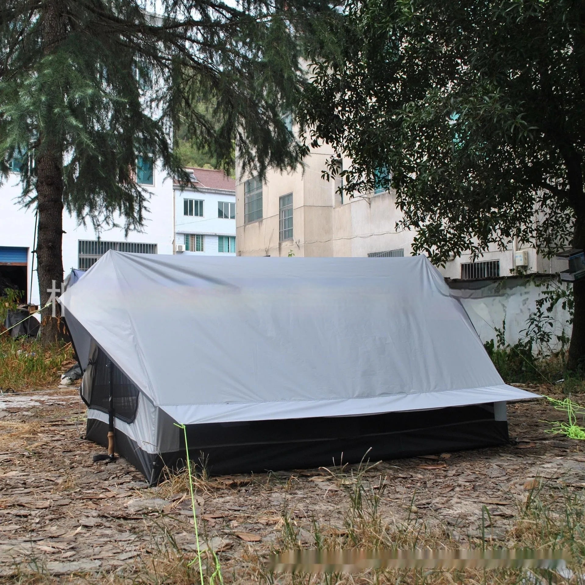 Brown A-line hiking tent pitched using trekking poles with guy ropes secured