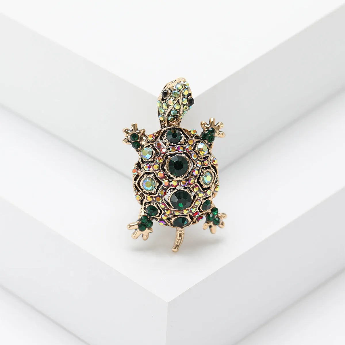 Close-up of a retro-style rhinestone turtle brooch in alloy, shown in blue, green and red colour options.