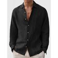 Man wearing a loose, long sleeve striped shirt in a cardigan style.