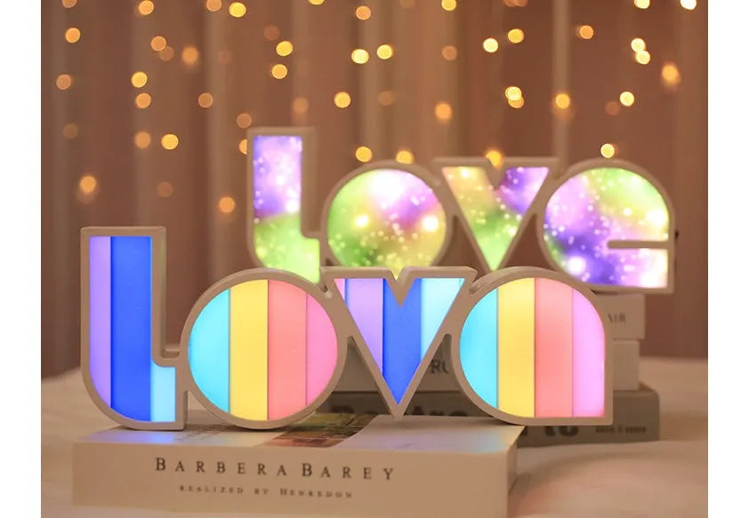 LED LOVE light with rainbow-coloured plastic lampshade on a desk