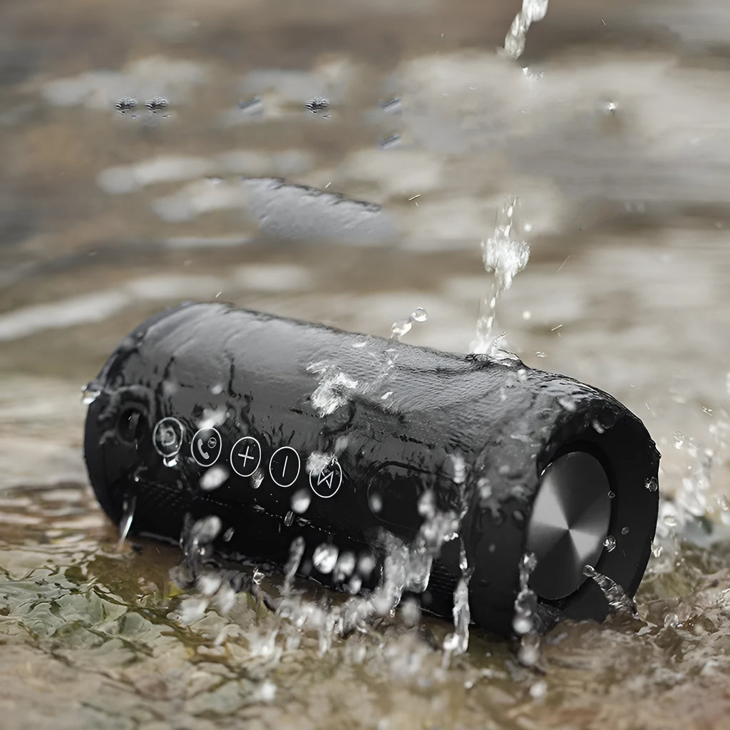 Black outdoor waterproof Bluetooth speaker with control buttons, shown in a garden setting.