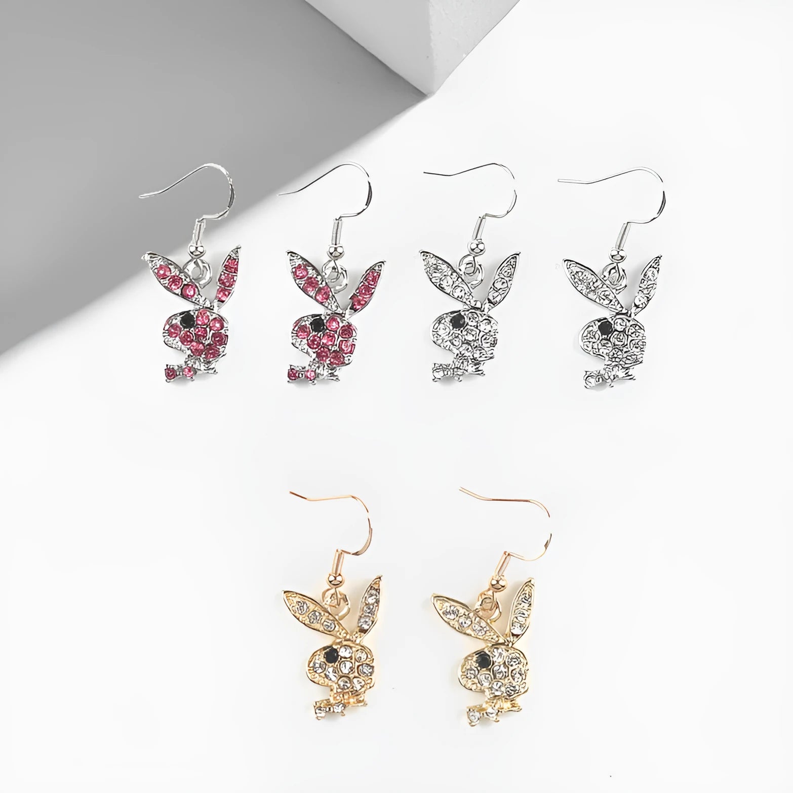 Close-up of a pair of sparkling rabbit silhouette stud earrings with cubic zirconia stones on a silver background.