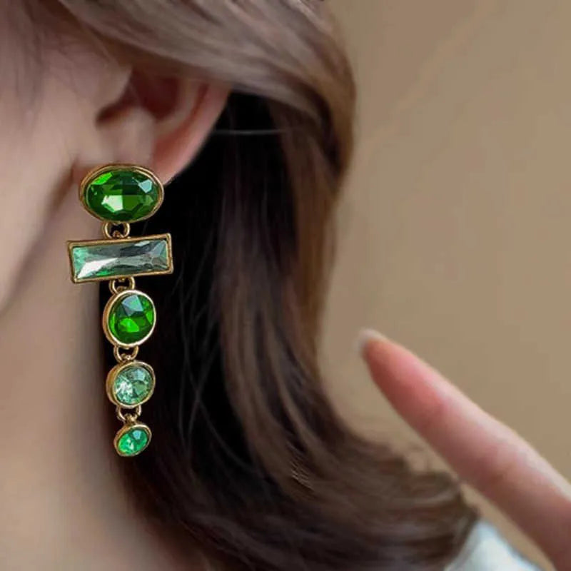 Pair of green gradient geometric ear studs with zircon details and a long tassel, on a white background.
