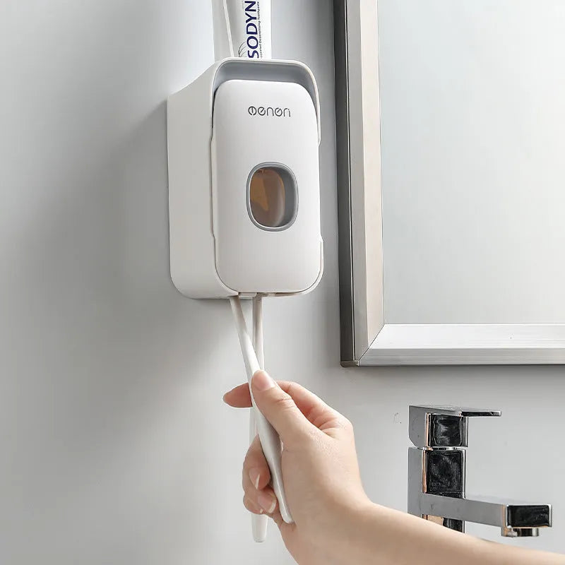 Blue automatic toothpaste dispenser mounted on a bathroom wall with a push-button for one-handed use.