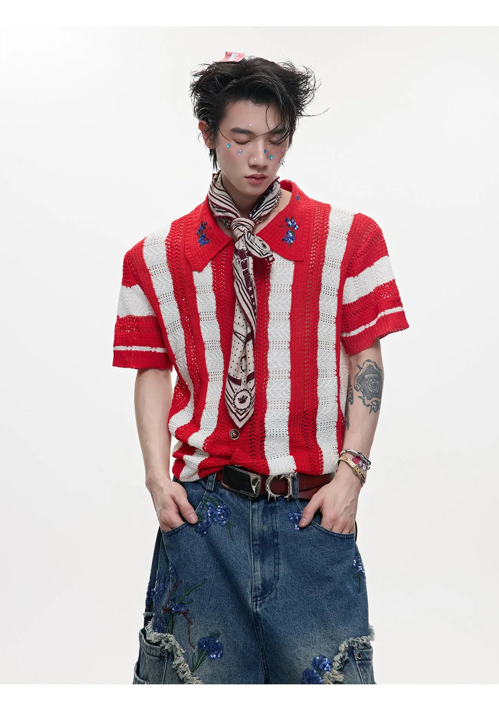 Man wearing a red and black patchwork striped knitted short-sleeved shirt with a loose fit.