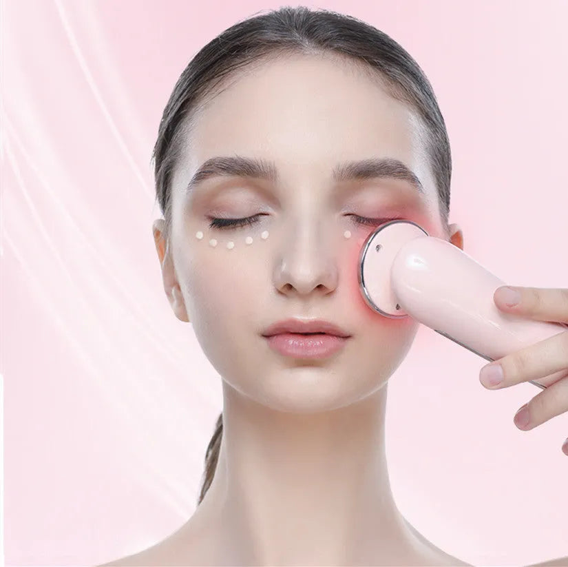 Pink and white rechargeable facial massager with red and blue light therapy functions on a clean surface