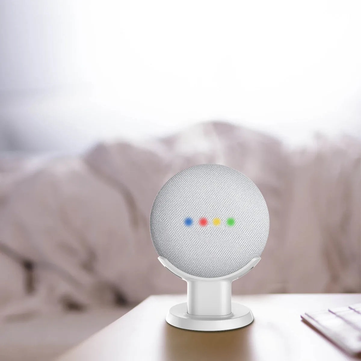 Black or white plastic stand holding a Google Home Mini voice assistant on a desk.