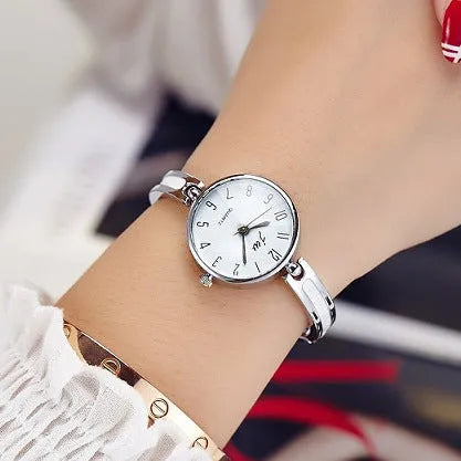 Gold dial quartz watch with steel strap and mineral glass mirror on light background