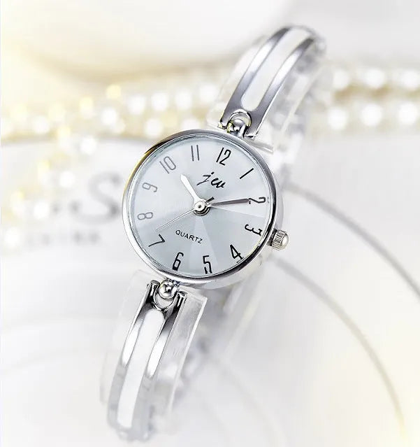 Gold dial quartz watch with steel strap and mineral glass mirror on light background