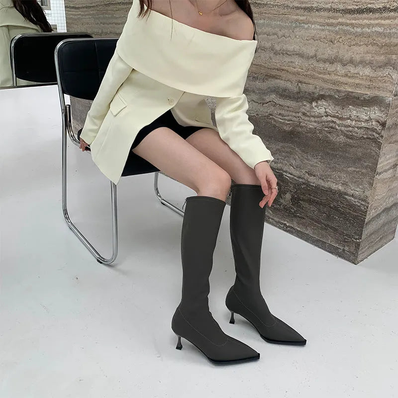 Women's pointed toe knee-high boots in black with a stiletto heel and a visible back zipper closure.