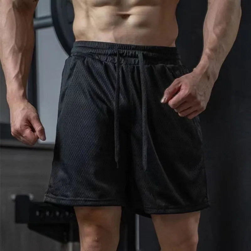 Men's loose-fit grey mesh sports shorts with quick-dry polyester fabric on athletic model