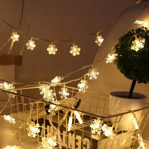 Battery powered LED snowflake string lights in warm white on a garden tree branch for Christmas decoration