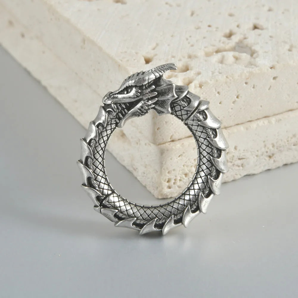 Pair of large antique silver dragon-shaped hollow-out earrings with geometric design on a plain background.