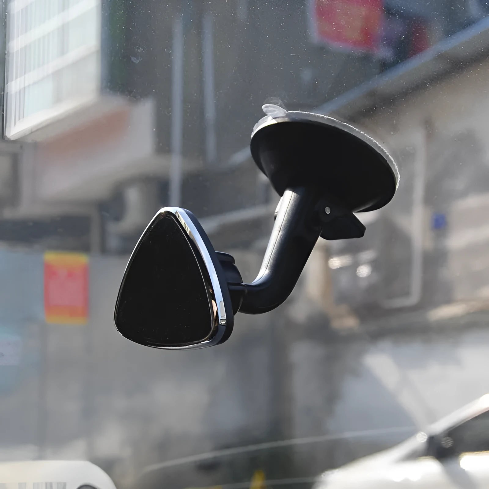 Black magnetic car phone holder mounted on a car dashboard, showing a smartphone attached.