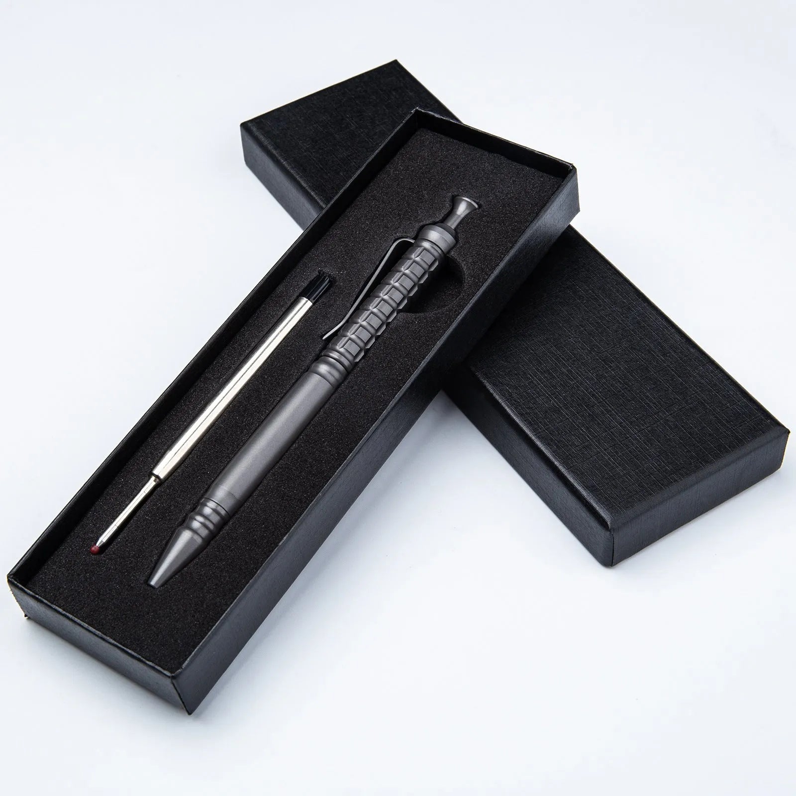 Gunmetal grey titanium alloy tactical pen with push-action mechanism on a gift box.