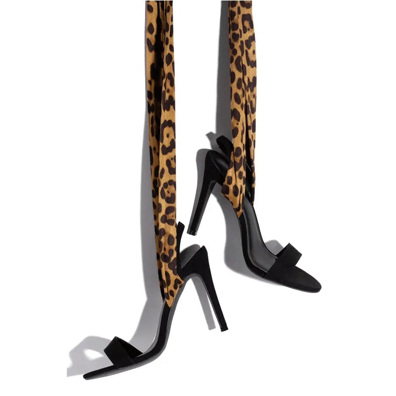 Light brown leopard print women's high heel sandals with cross straps and a thin stiletto heel on a white background.