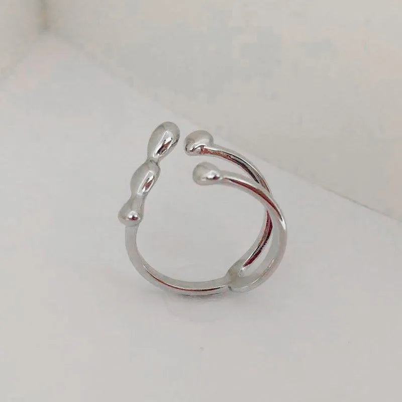 Gold tone brass ring with open circle design and central sphere on a person's finger.