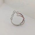 Gold tone brass ring with open circle design and central sphere on a person's finger.