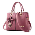 Retro-style handbag in black with a zip top and a single shoulder strap, shown with a phone and wallet inside.