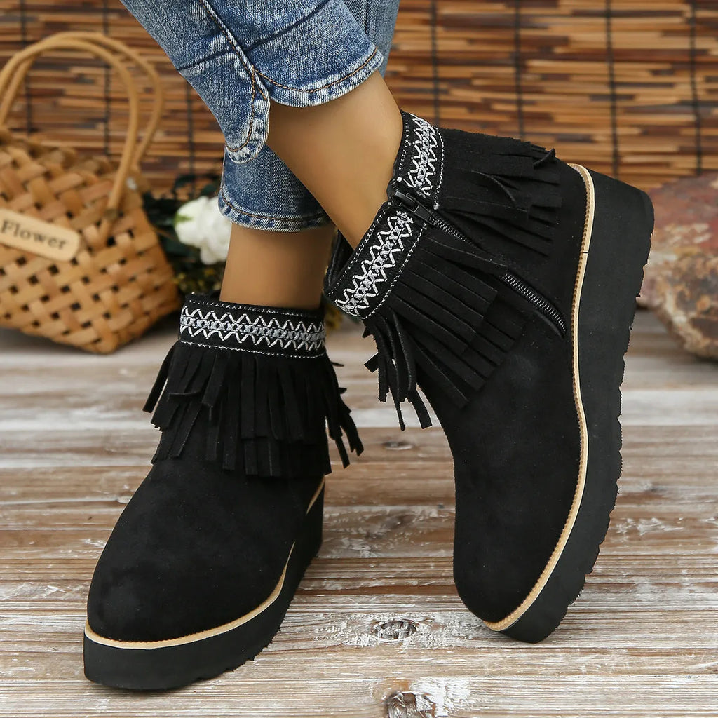 Women's black suede wedge bootie with a thick sole, side zipper, and tassel detail.